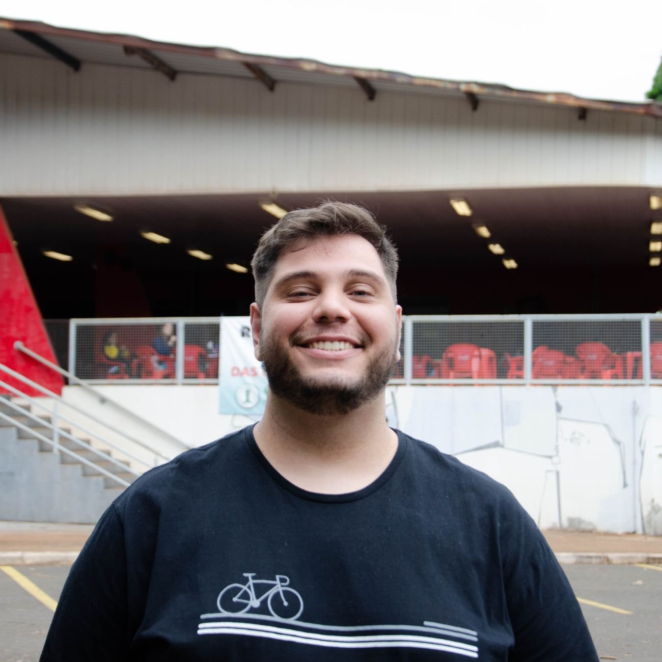 A young man smiling confidently outside a modern building.