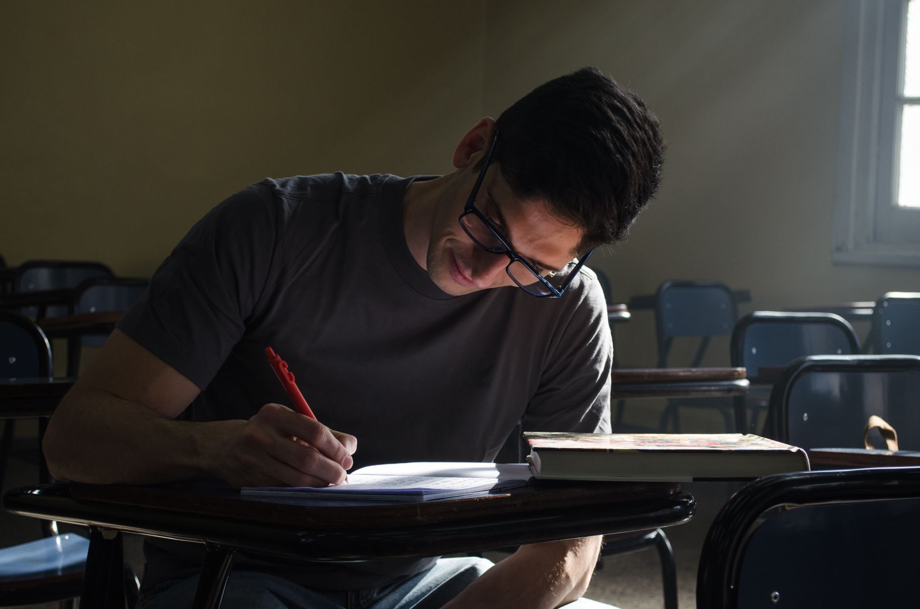 Young man studying at a desk, focused on writing notes.