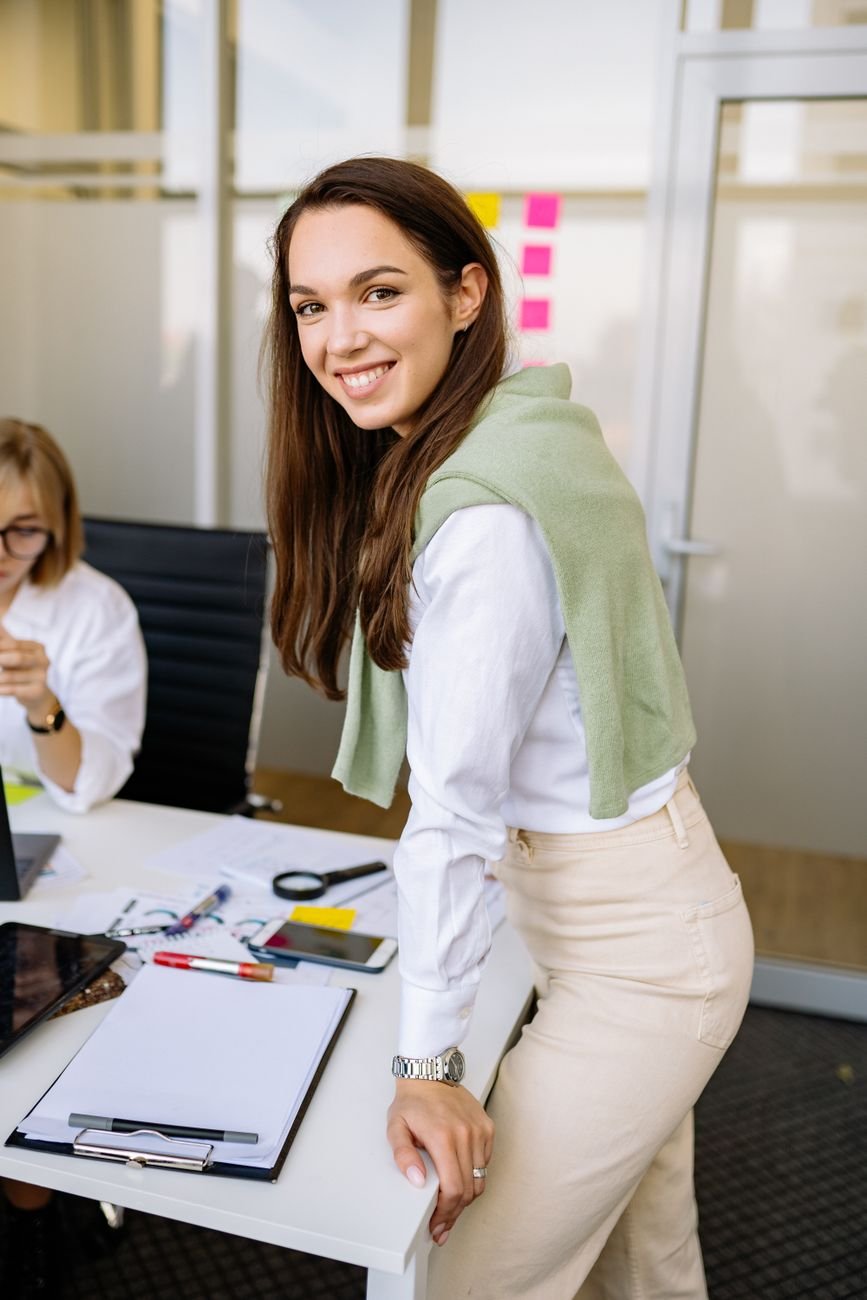 Confident young woman smiling at camera in a professional office setting.